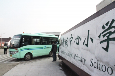 鎮村公交校車按順序駛出校園送學生回家。